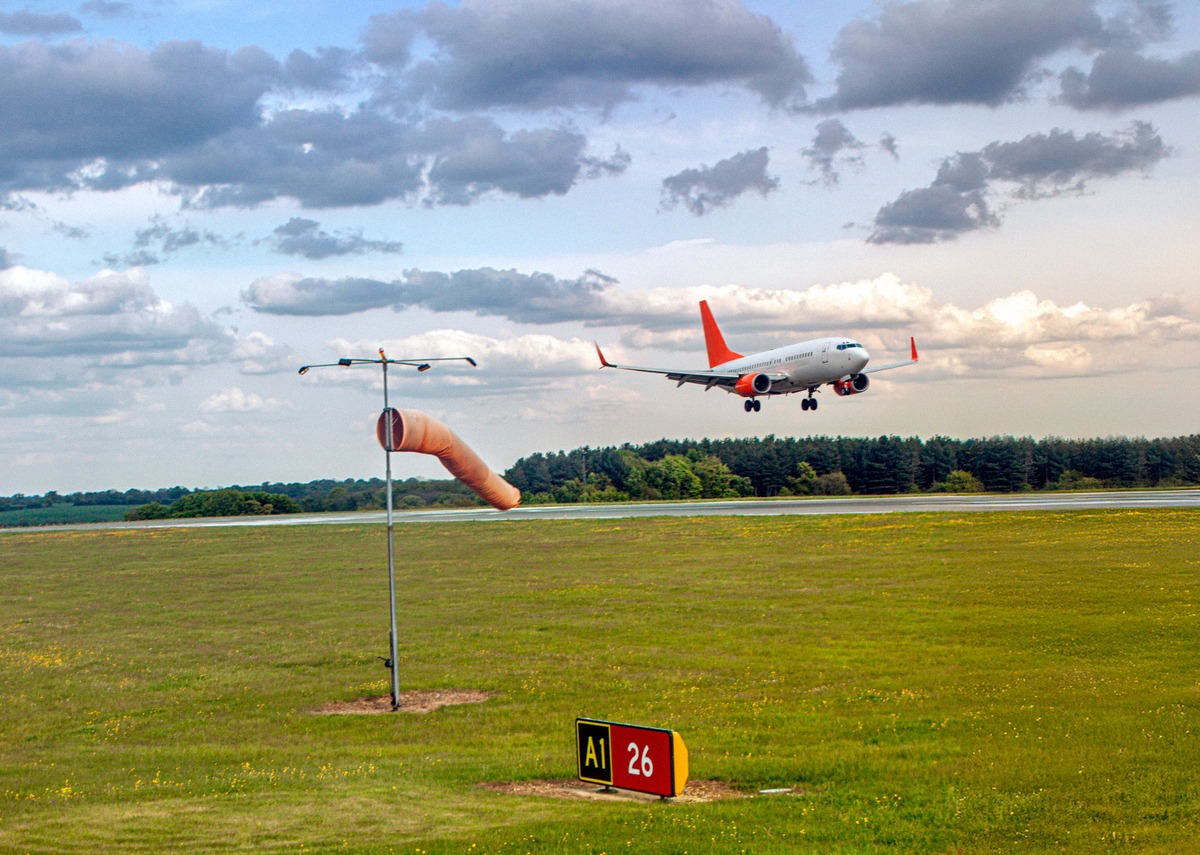 Passagierjet im Landeanflug auf den Flughafen Luton, davor ein Windsack